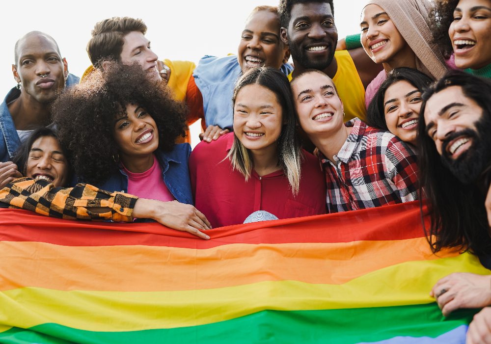 Crowd of multiracial people having fun together during LGBT pride parade outdoor - Diverse young friends from diverse cultures holding rainbow flag - lgbtq+ affirming mental health care in orange county california