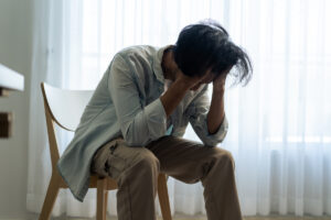 man sitting on chair with head in his hands having a panic attack - signs of repressed trauma in adults